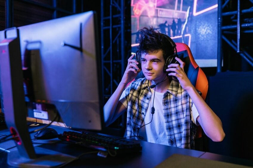 Kid playing in front of his gaming monitor while wearing a gaming headset